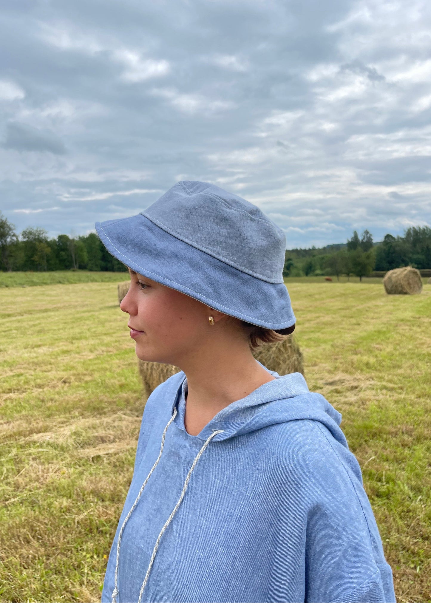 Person wearing a blue bucket hat in a field with a lake in the background